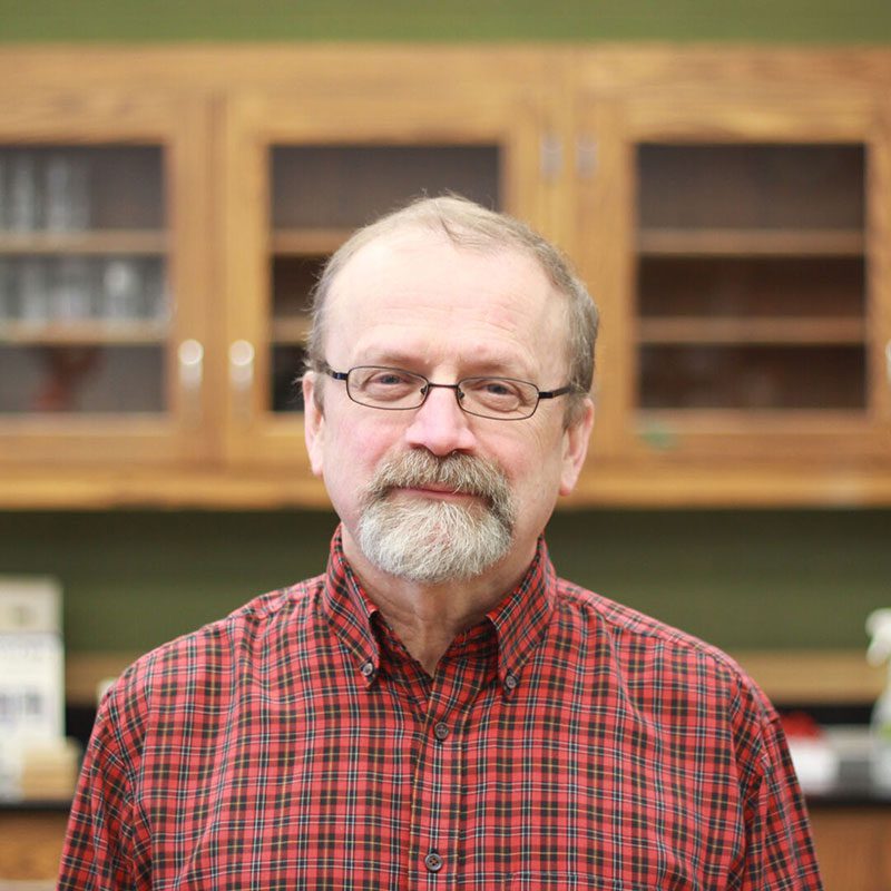Houghton Universityprofessor Don Wilcox standing in lab.