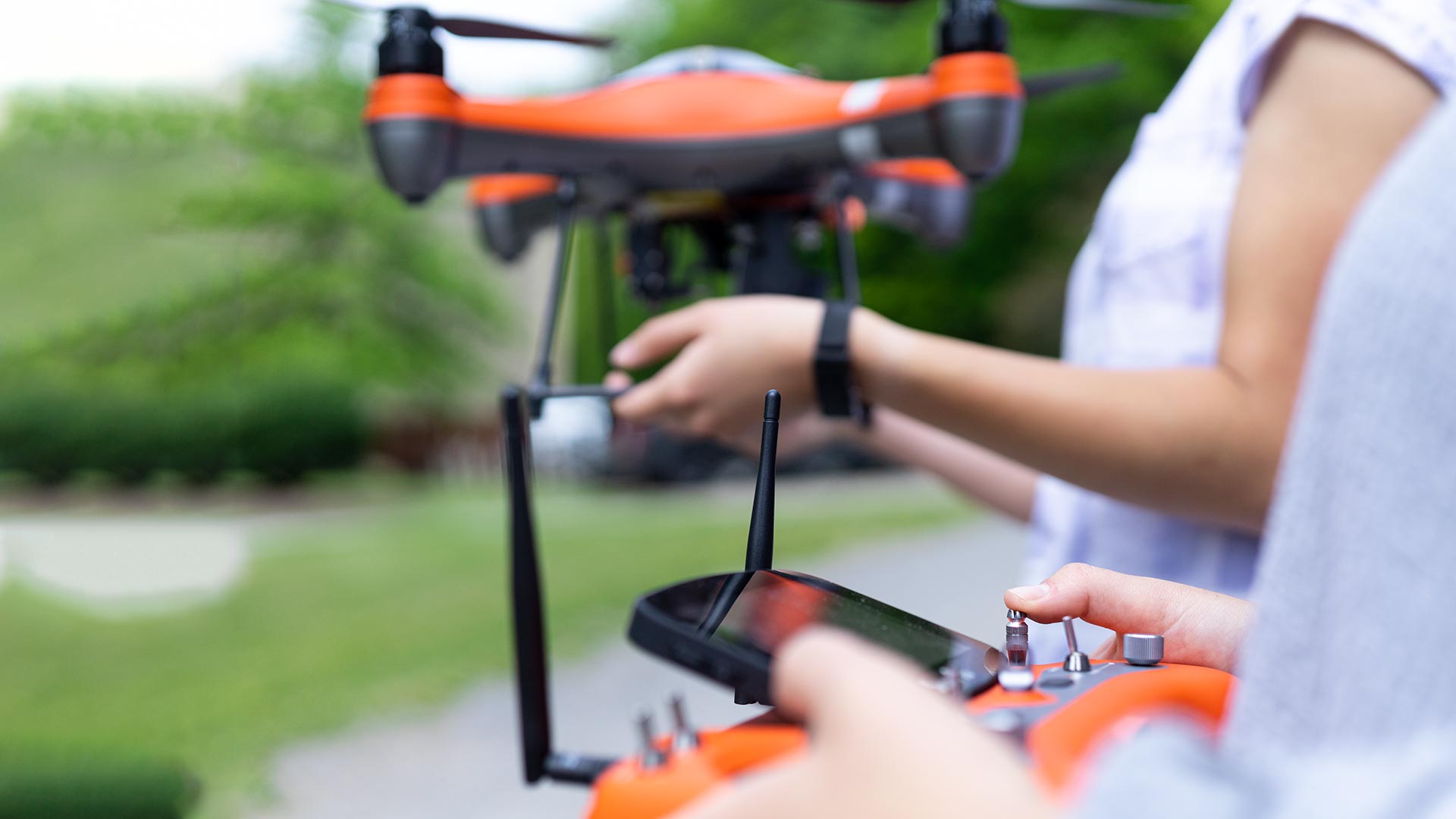 two students handling drone outdoors
