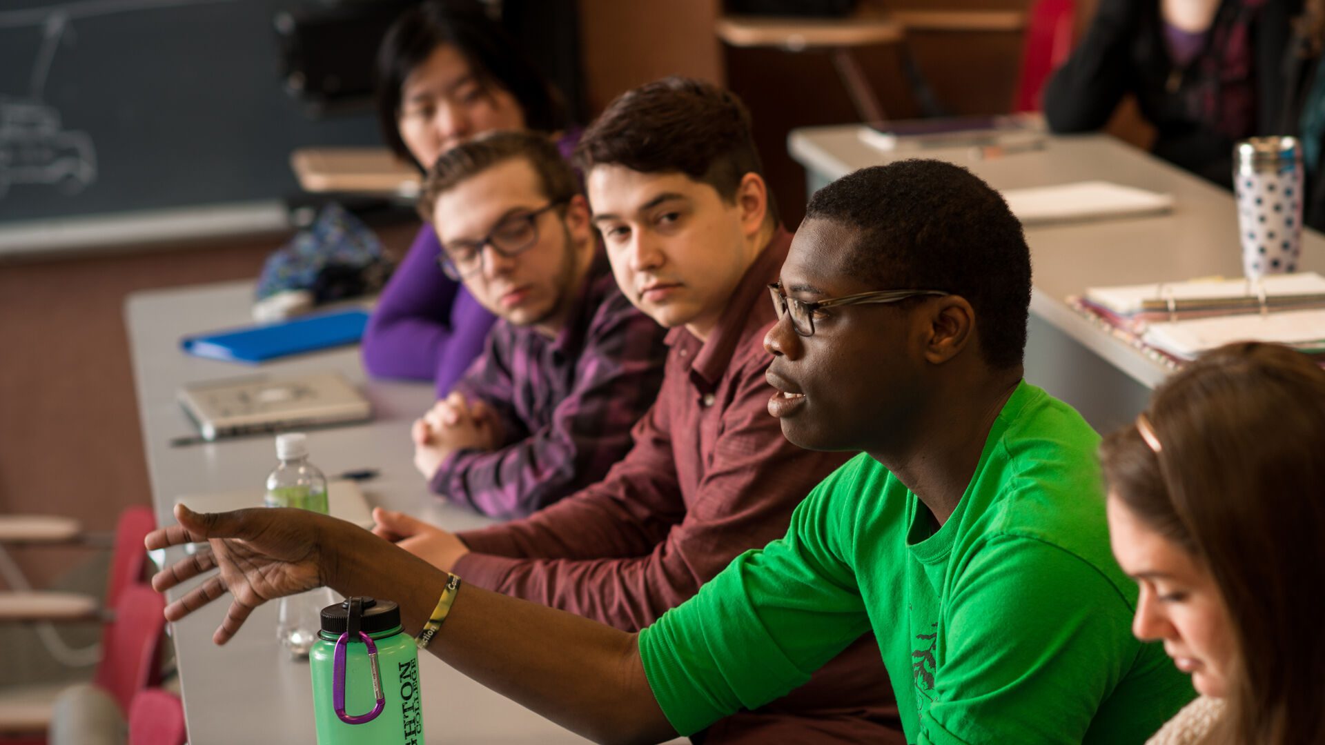 Students sitting at table discussing a topic in a Christ-centered learning environment.