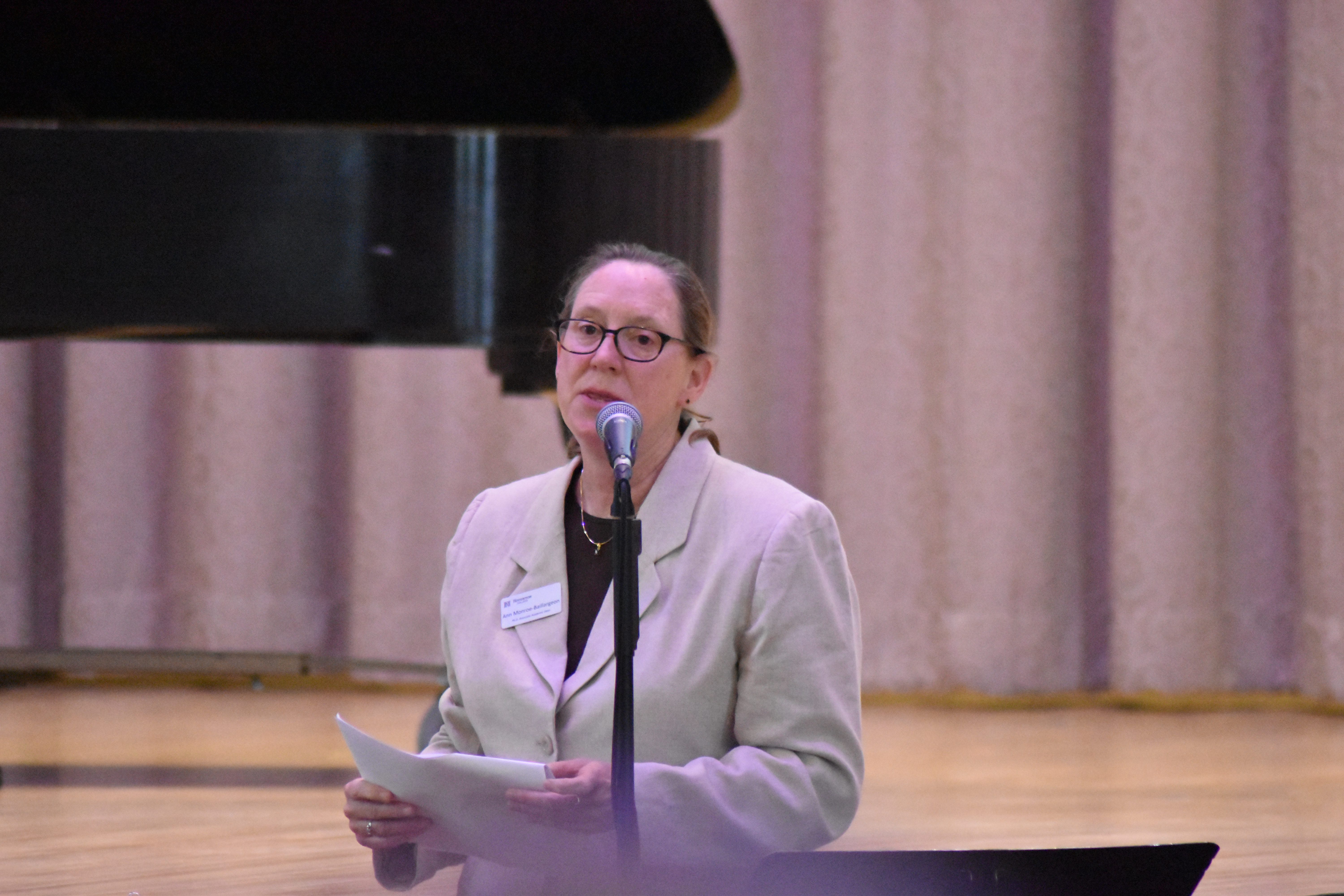 Woman standing at microphone addressing the audience.