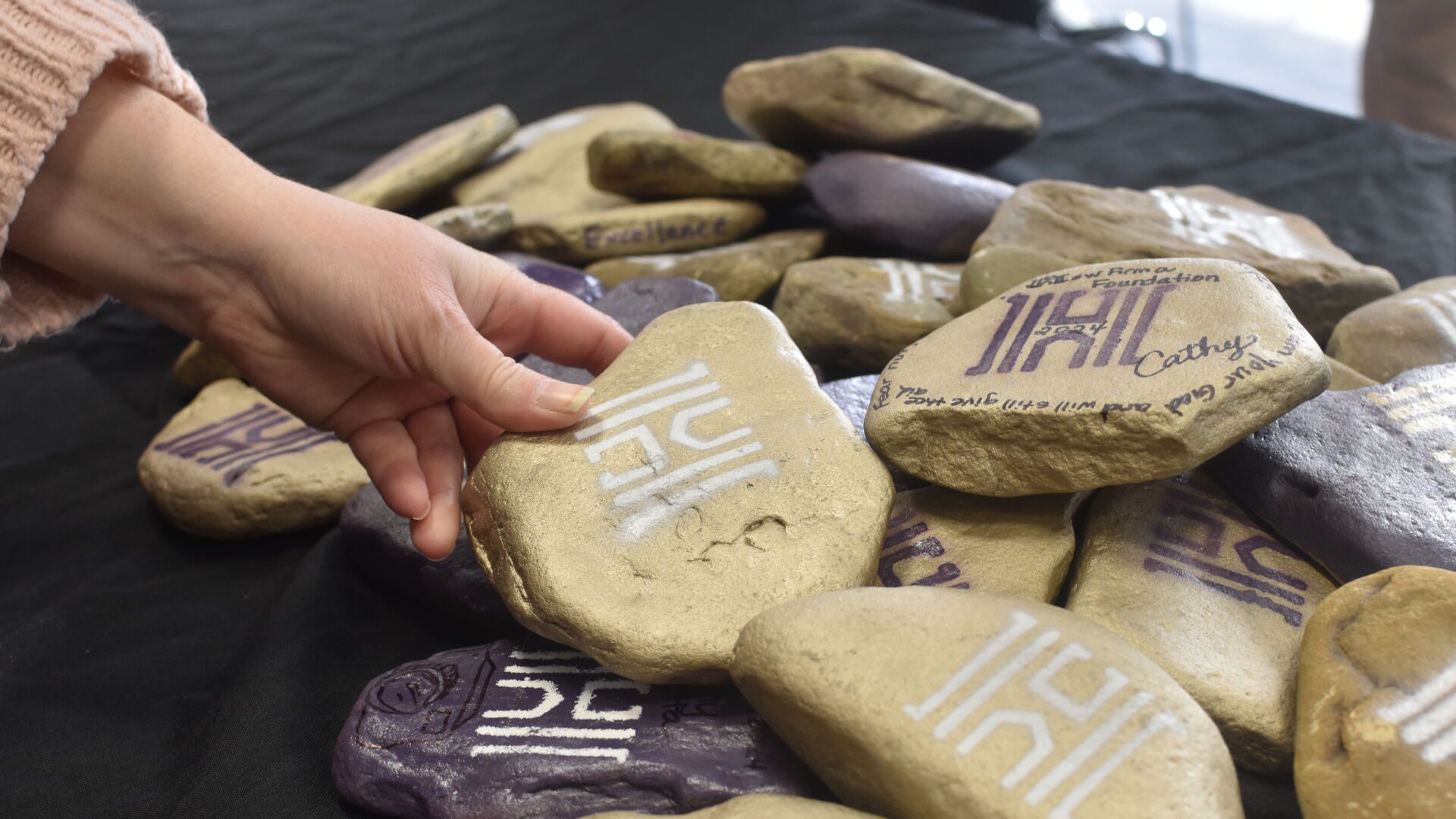 Women holding a stone with the ����ר�� logo on it.