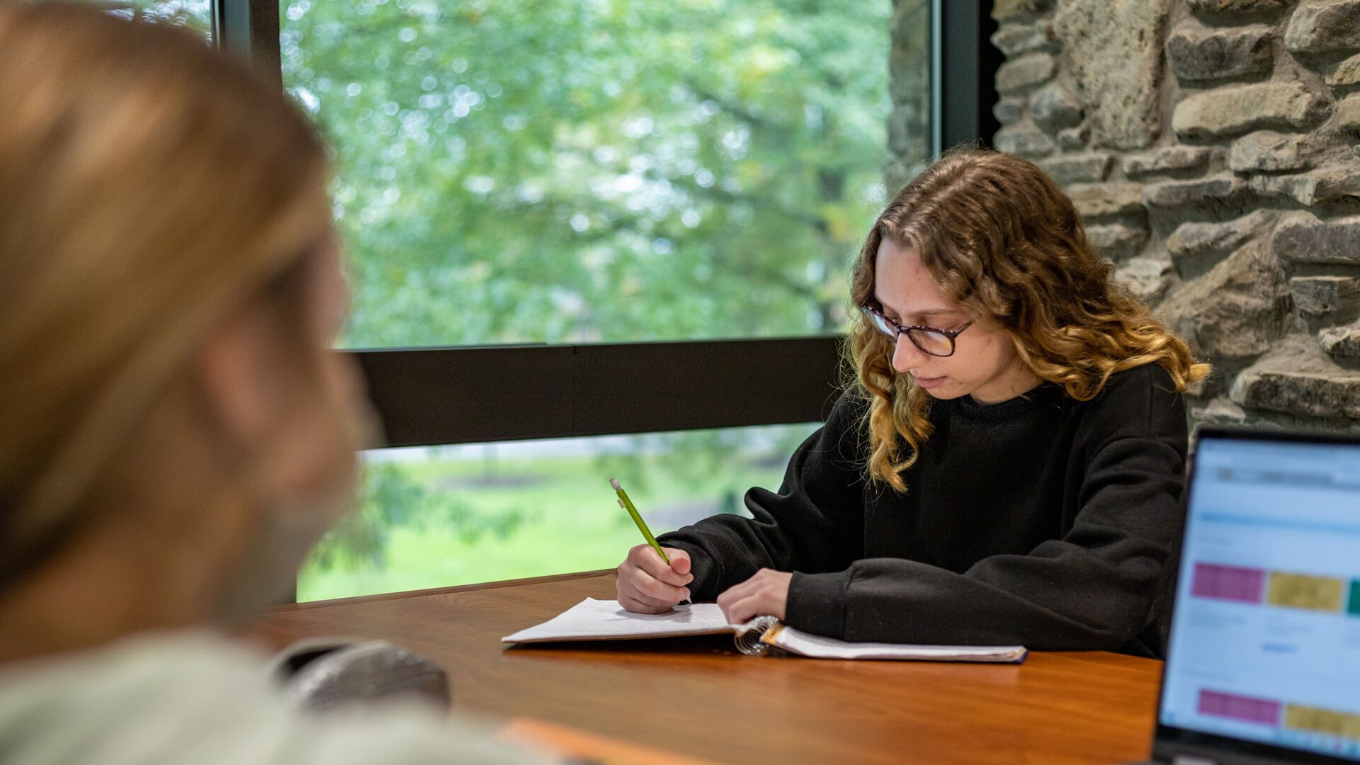 Jennifer Page sitting at table writing in her notebook.