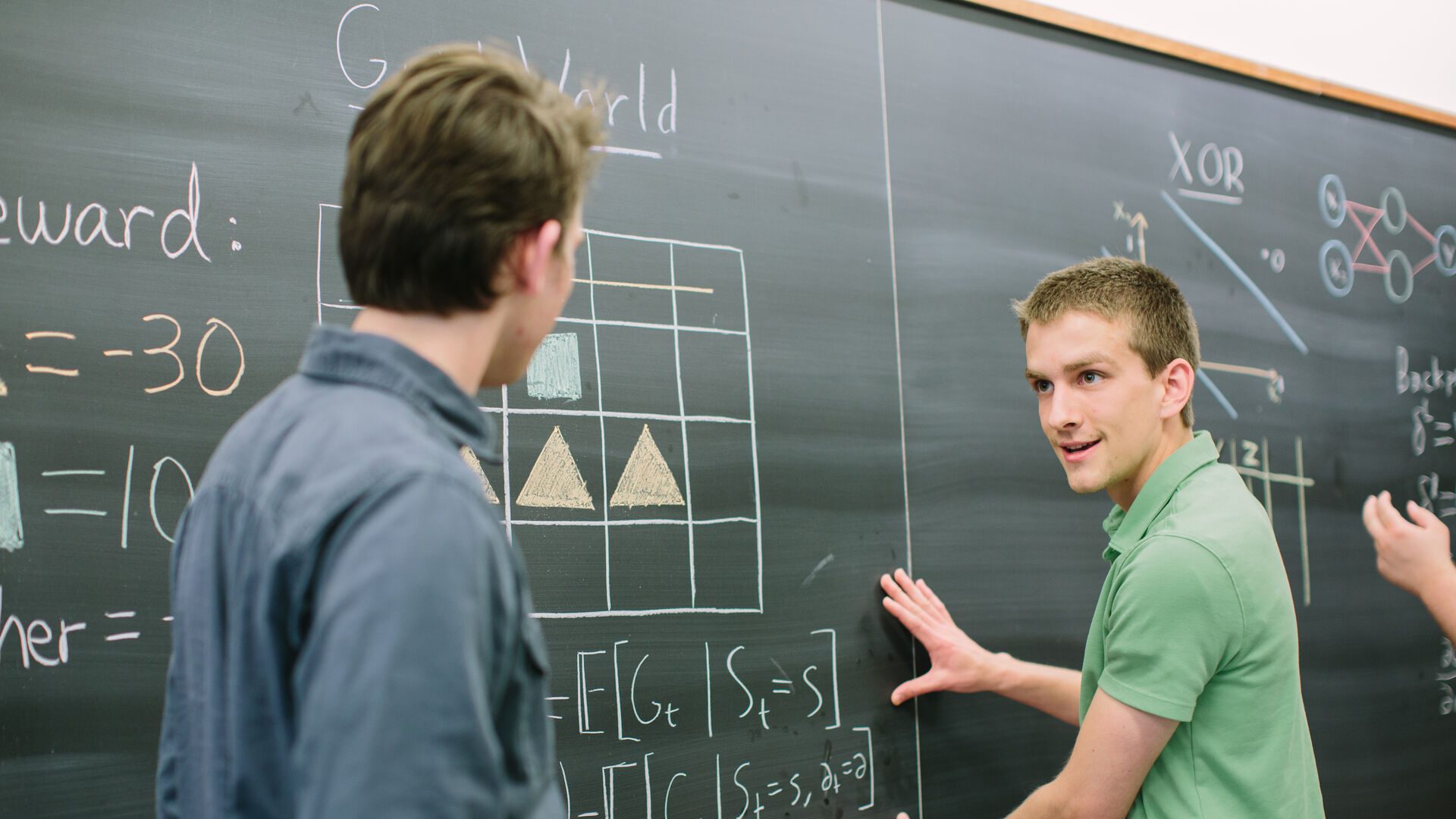 Two ����ר�� computer science majors working through problem at the chalkboard.