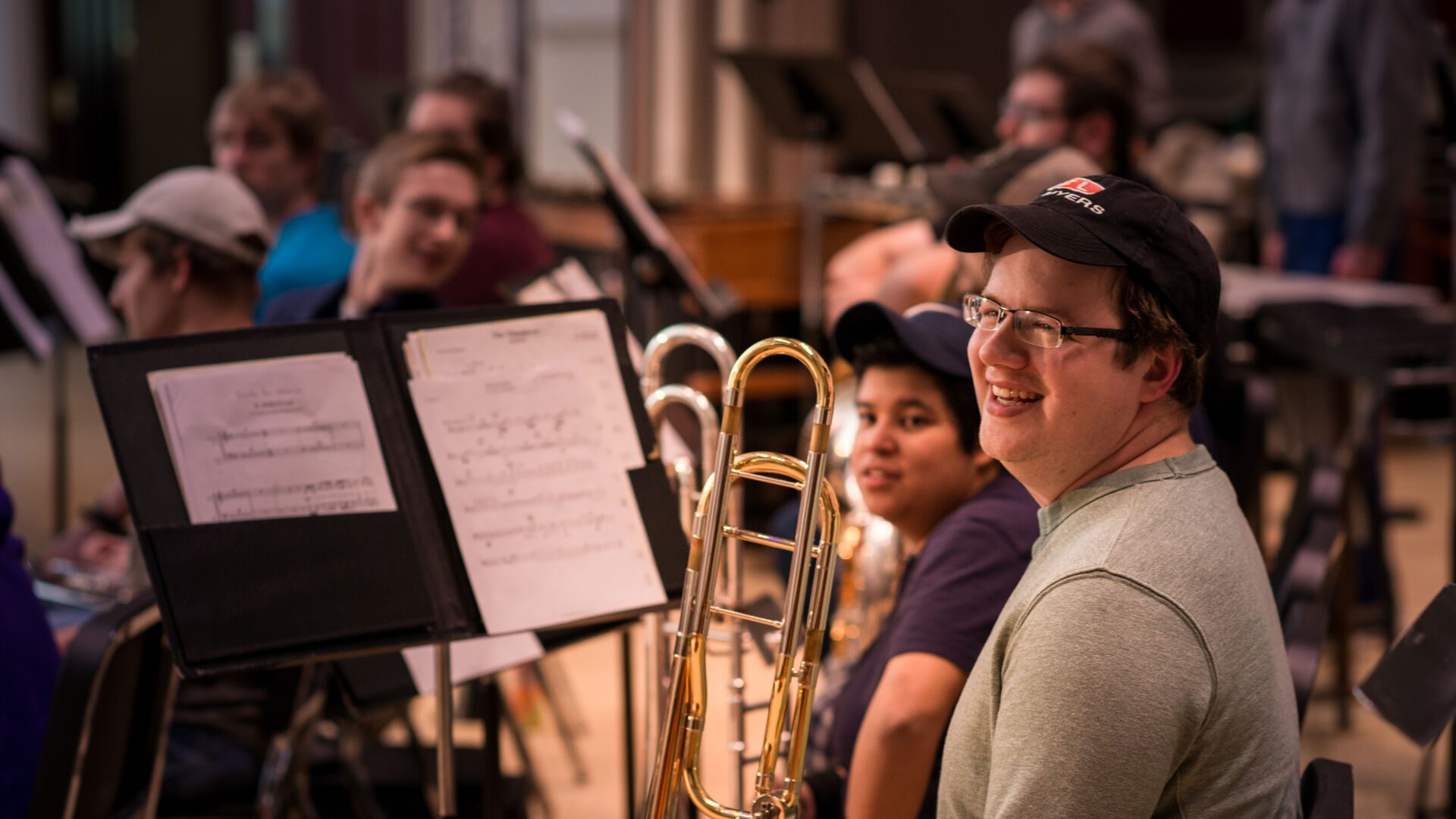 Student sitting and smiling holding his trombone.