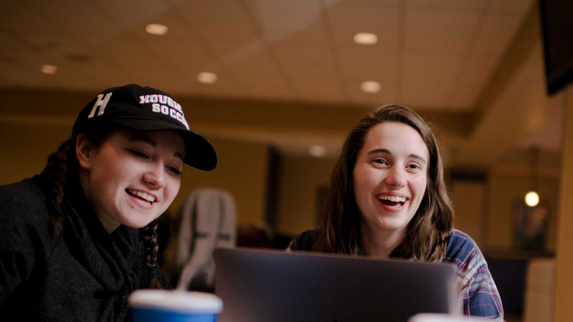 Two ����ר�� students sitting at table with drinks and laptop.