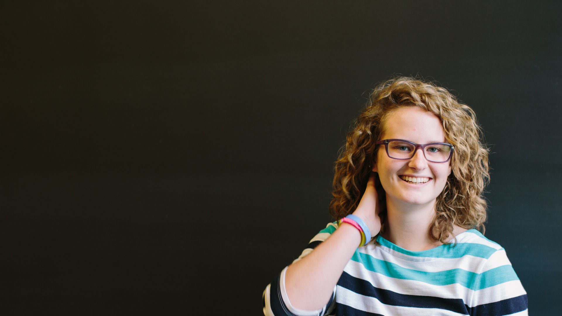 Student smiling standing in front of blackboards.