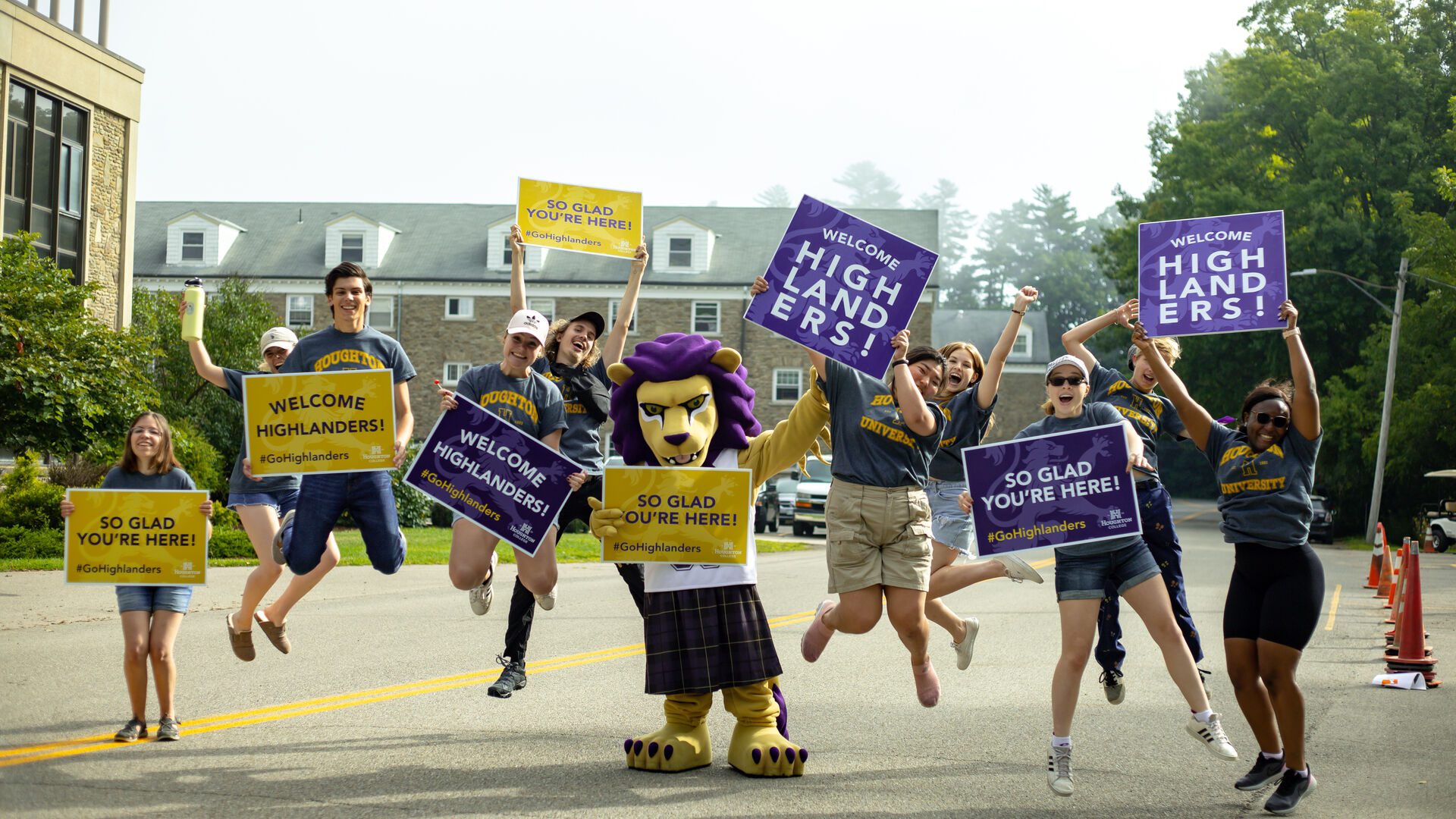 Group of ����ר�� students holding signs and jumping in the air welcoming the incoming class during move-in.