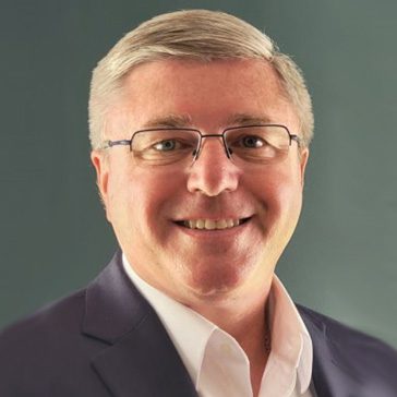 Roger Mattice with suit coat wearing glasses.