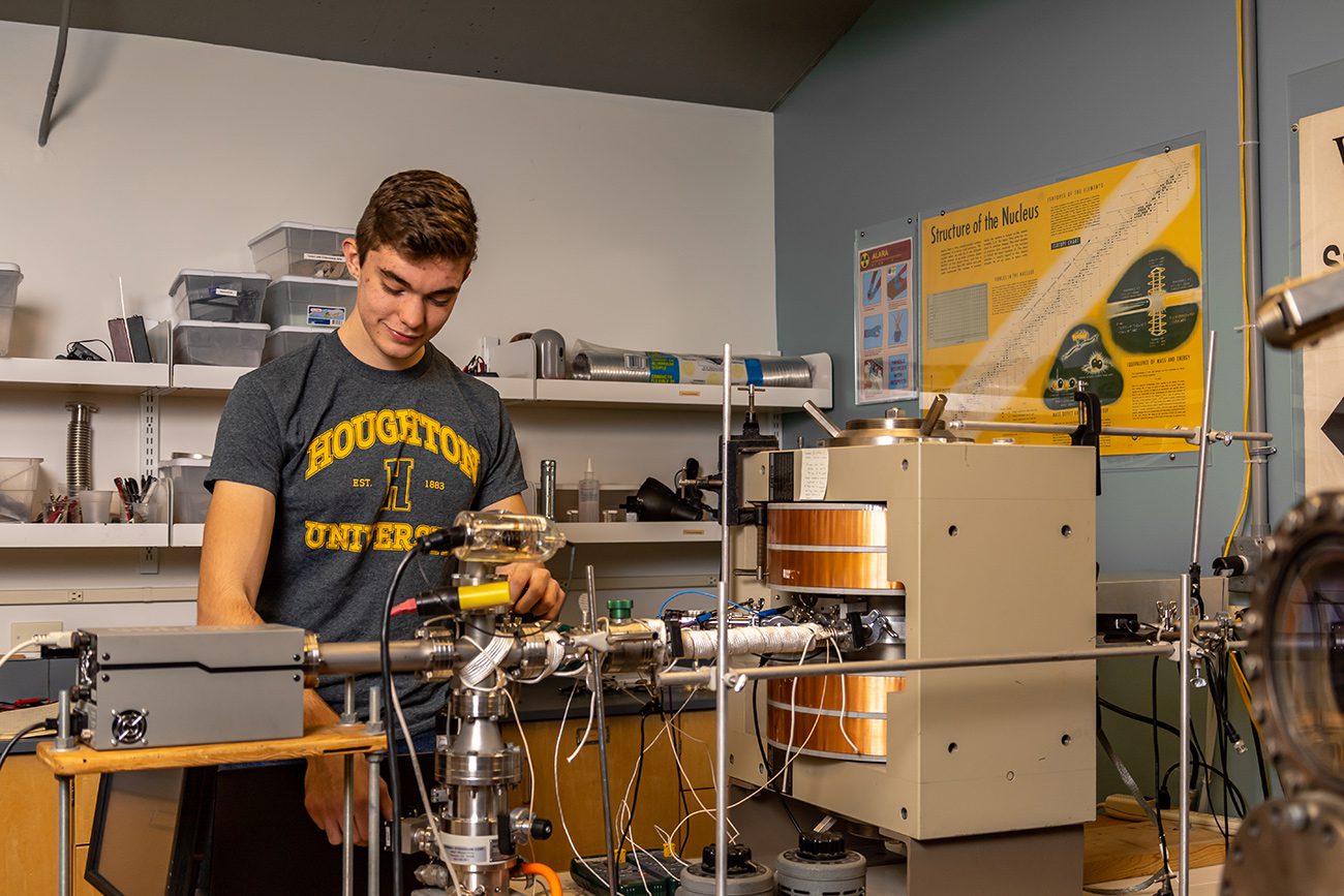 Houghton Universitystudent working with instruments in physics lab.