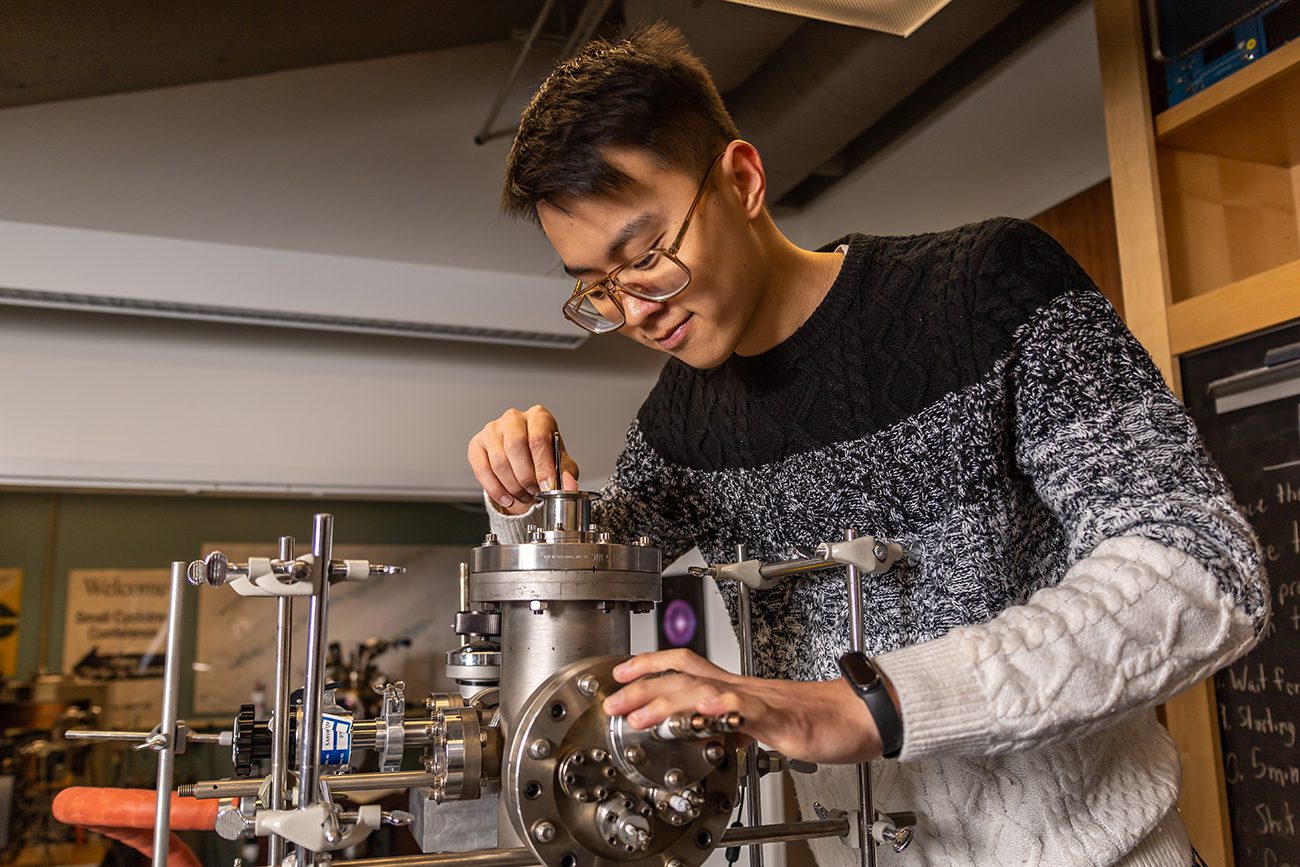 Houghton Universityphysics student working with instrument in physics lab.