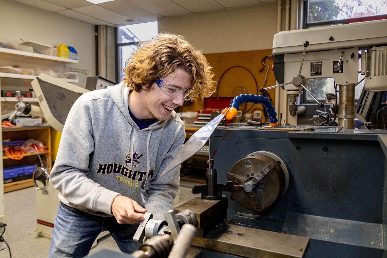 Houghton Universityphysics student working with machinery in physics machine lab.