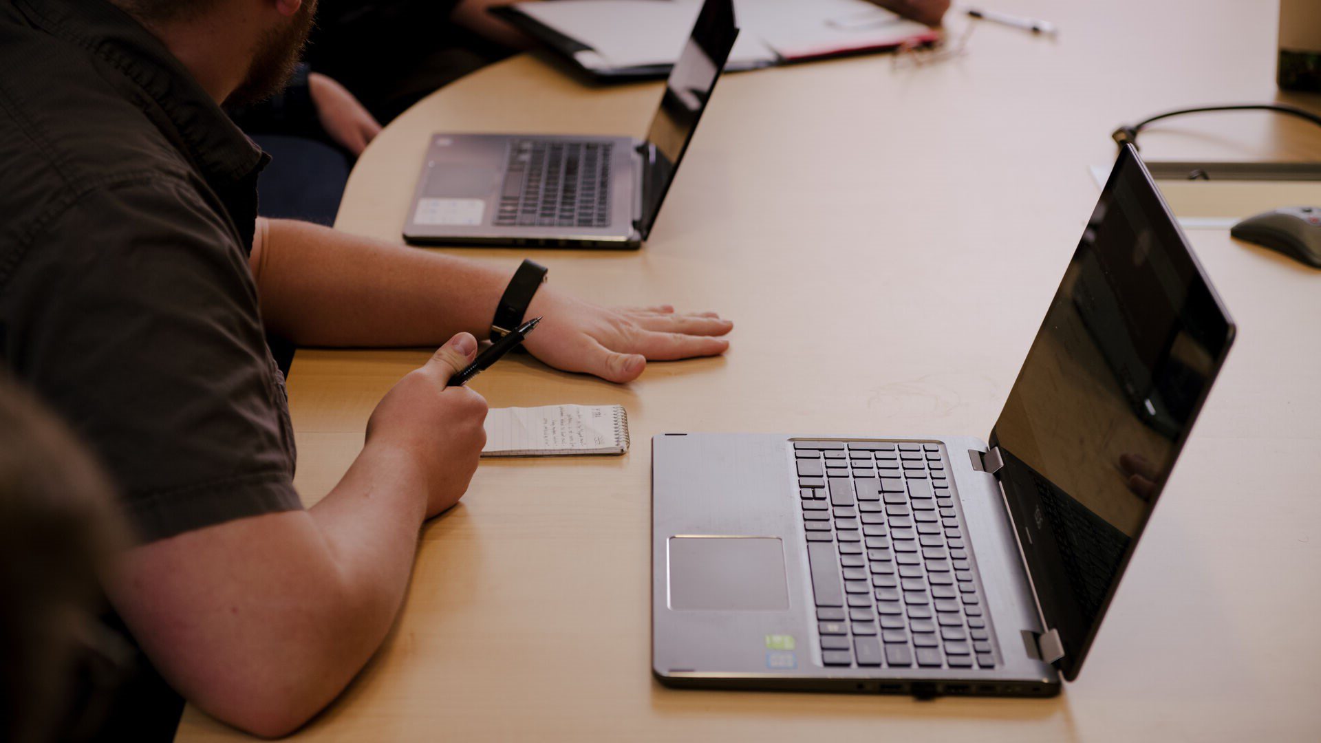 Houghton Universitystudent sitting at conference table with open laptop.