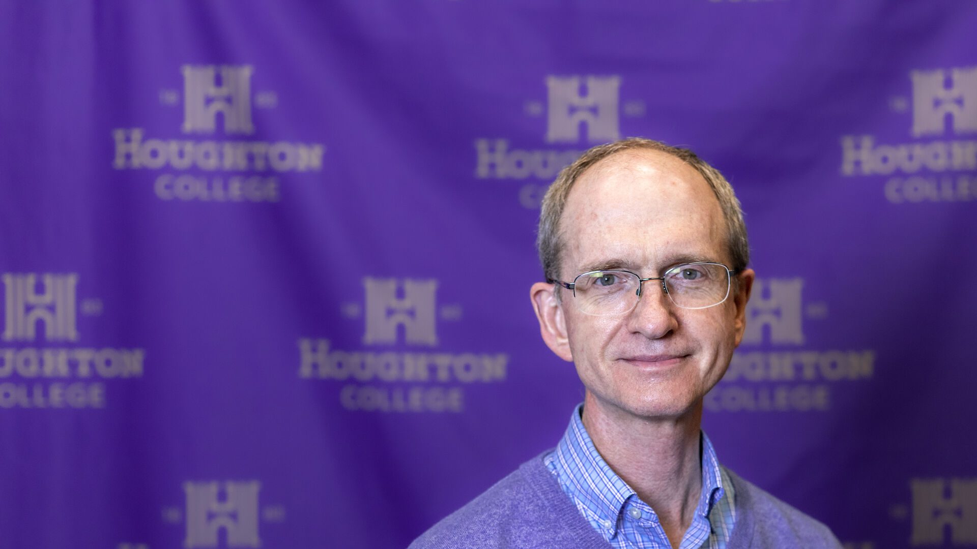 Houghton UniversityProfessor Marcus Dean standing in front of ����ר�� step and repeat banner.