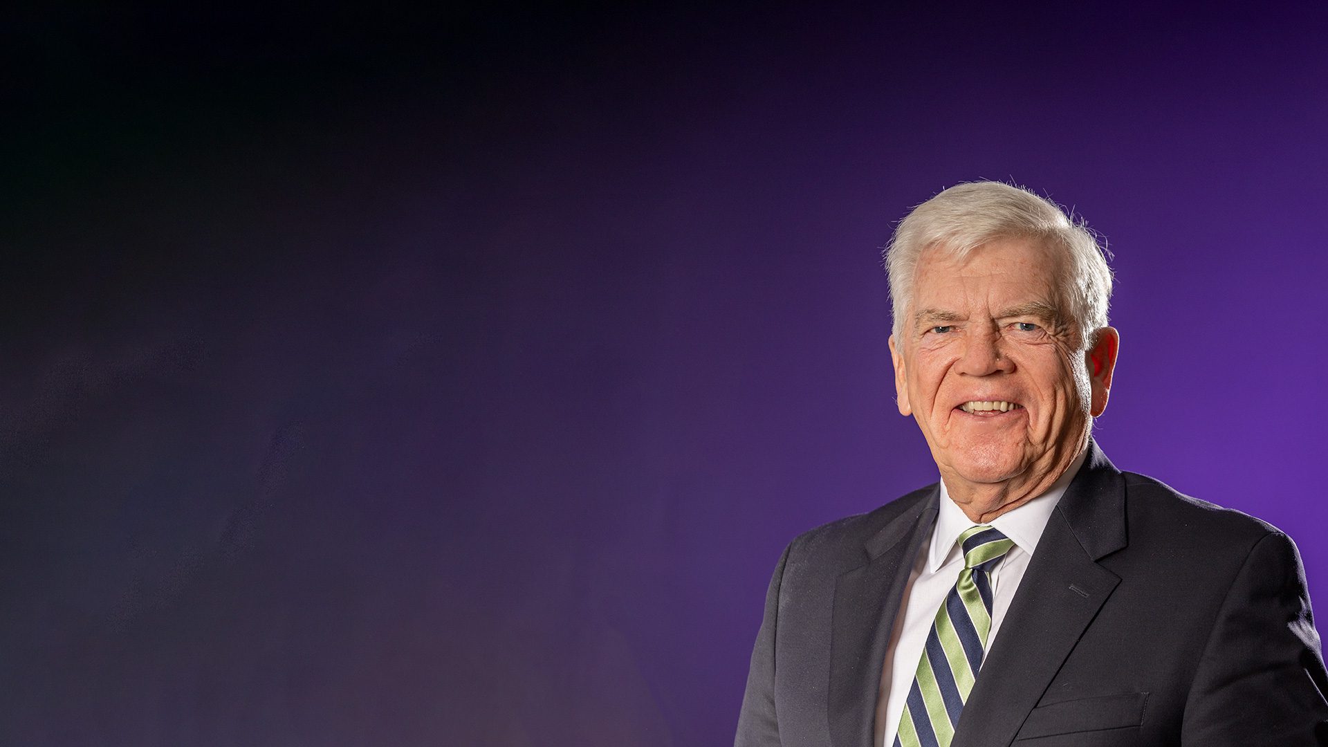 Dr. Ralph Kerr smiles at the camera in front of a purple background