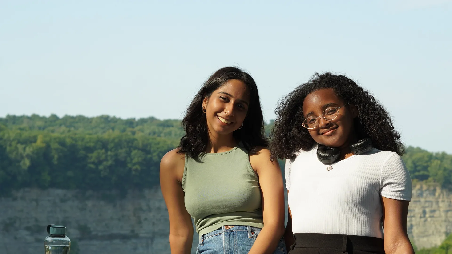 Two ����ר�� international interconnect students leaning against rock ledge in front of scenic vista.