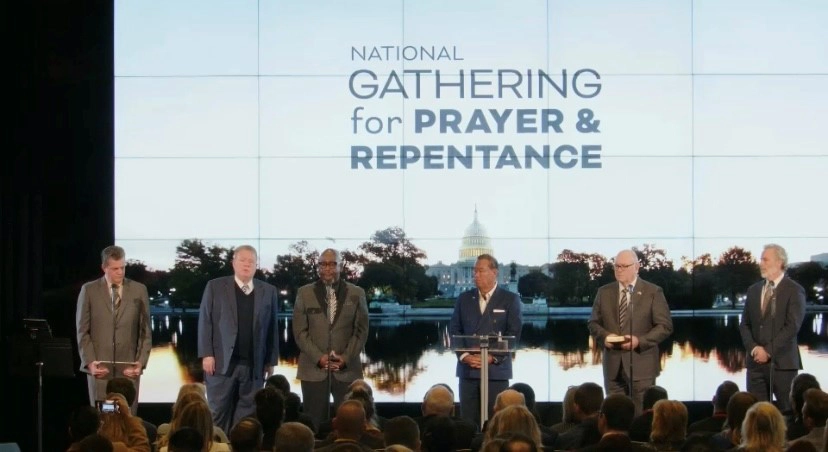 Six individuals standing on stage during the National Gathering for Prayer and Repentance in D.C.