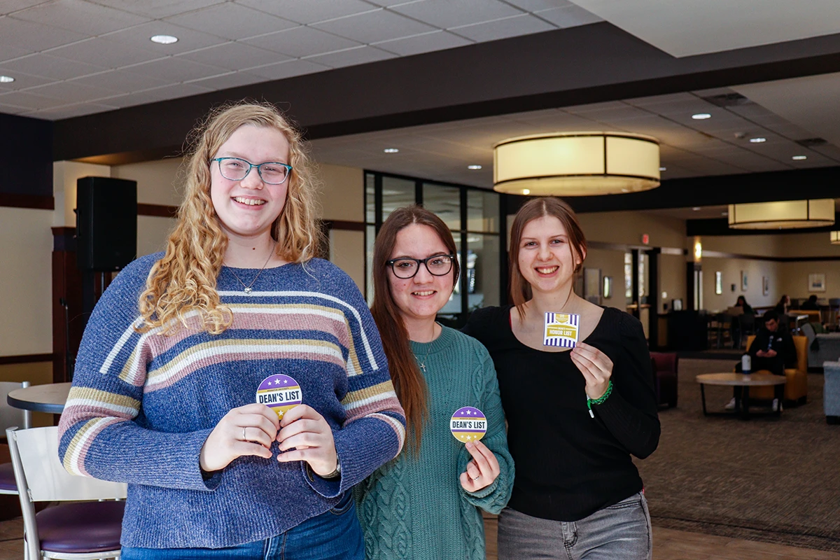 Three ����ר�� academic honors students standing together with sticker badges.