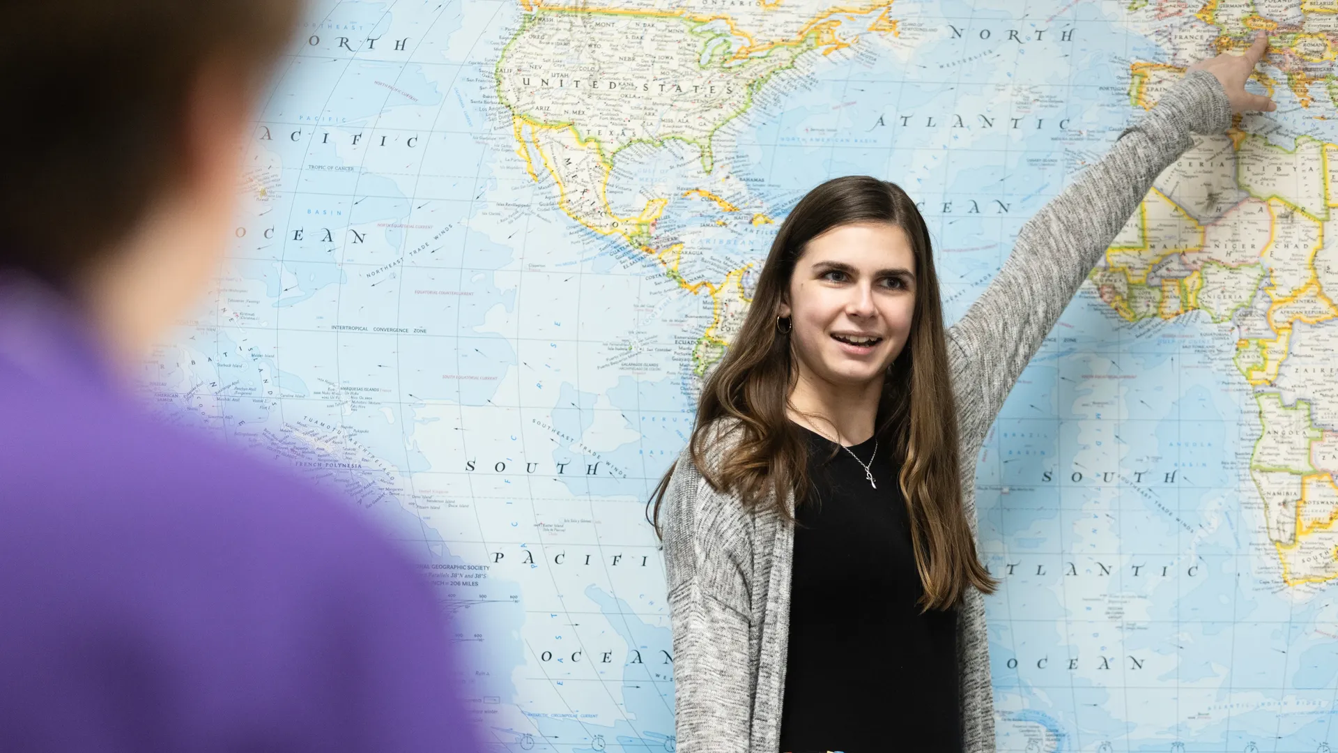 Houghton UniversityMAT in secondary education student pointing at world political map as they teach in class.