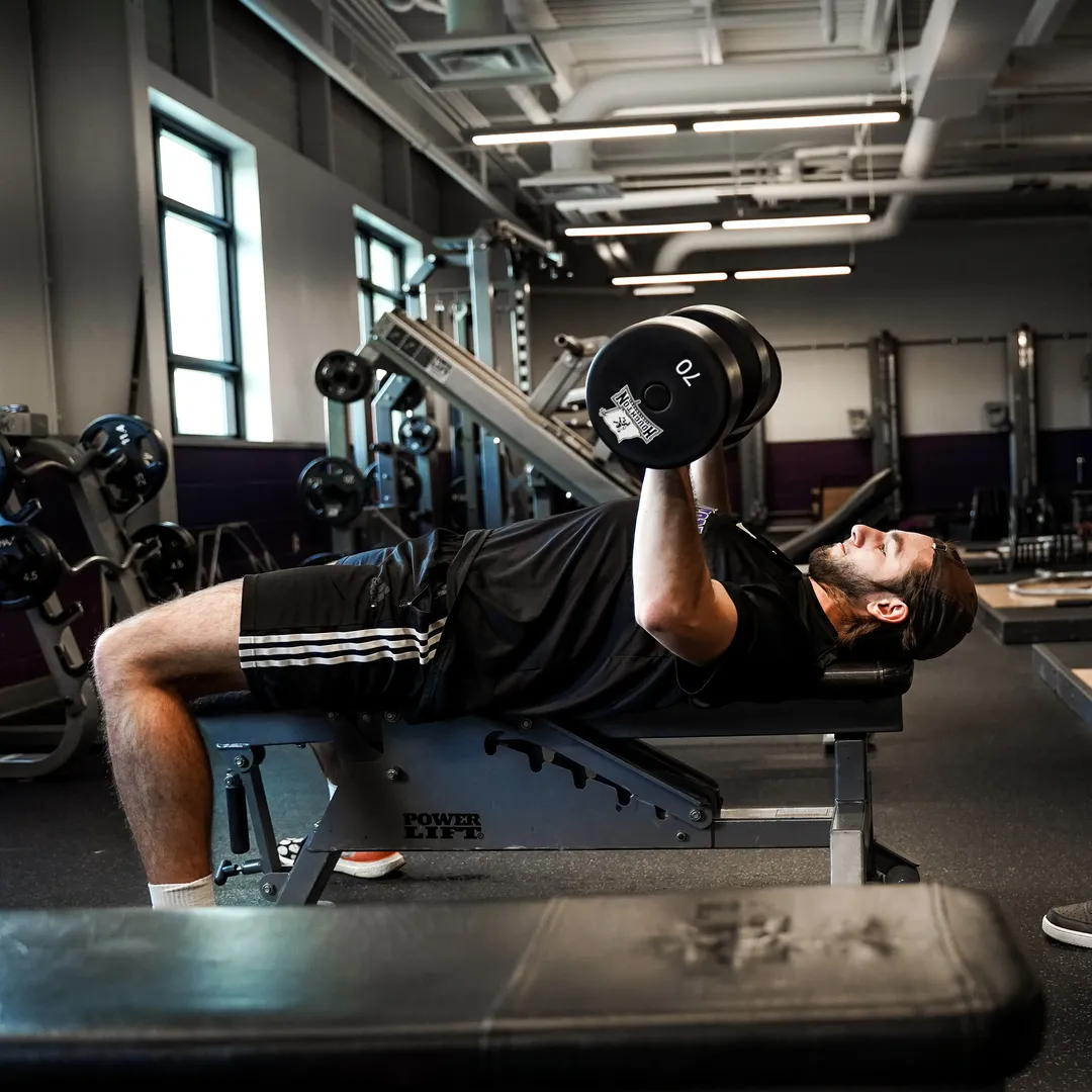 Houghton Universitystudent athlete lifting weights in fitness center.