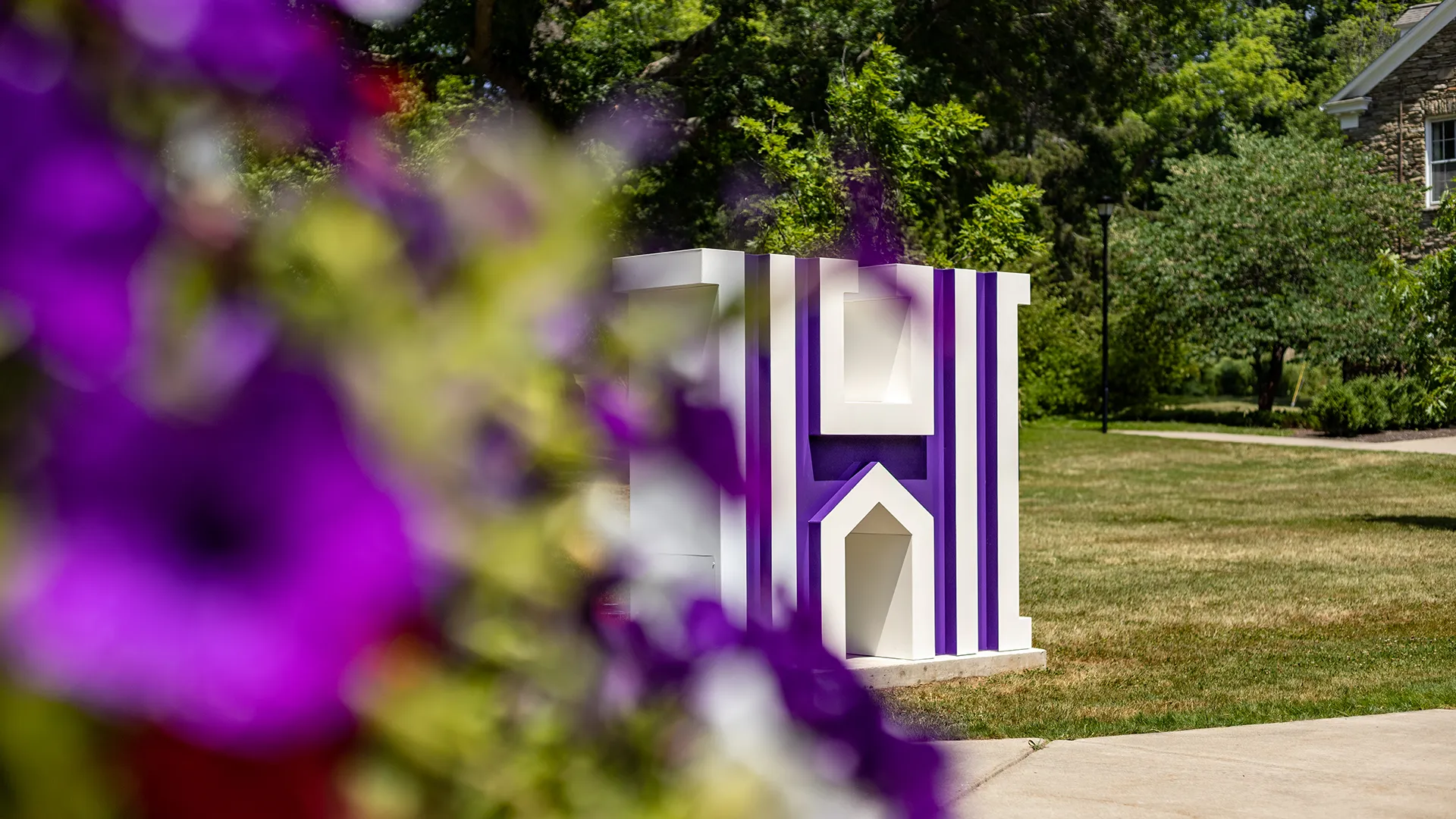 View of ����ר��'s H through purple flowers in the summer.