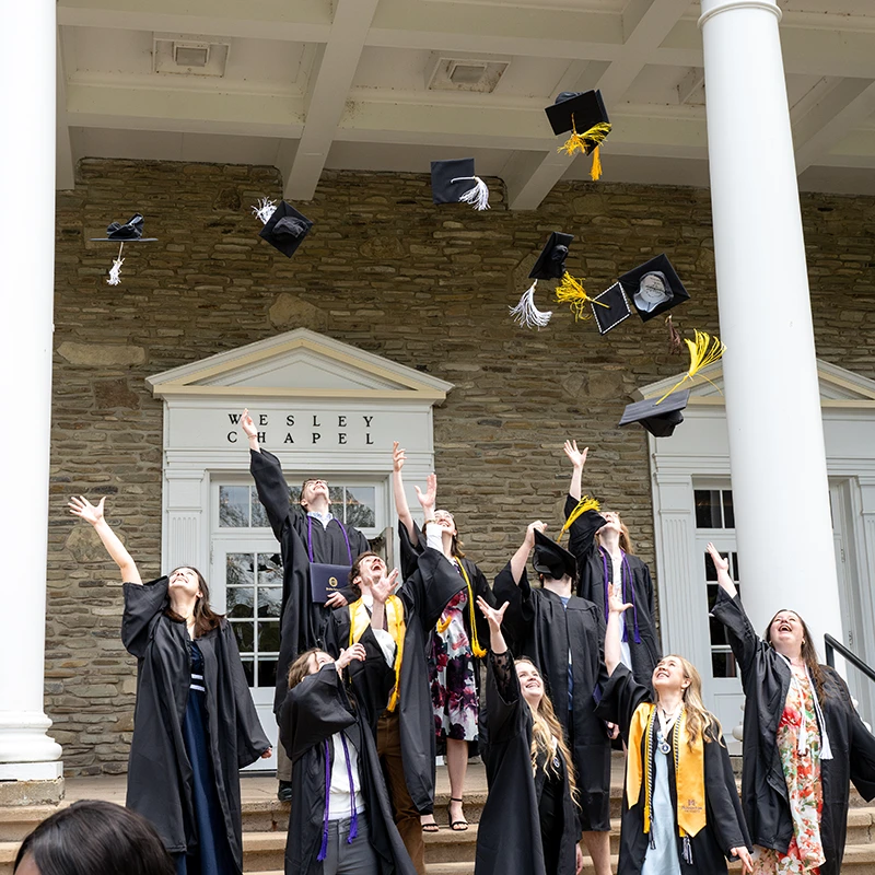 Houghton Universitygraduates throwing their caps in the air after commencement.