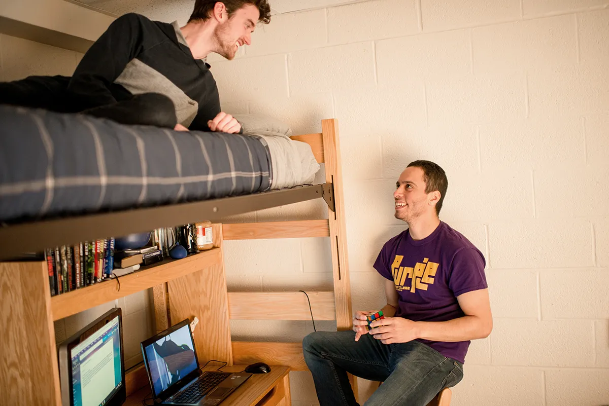 Two ����ר�� students in Shenawana Resident Hall room talking to each other at desk and bunk bed.