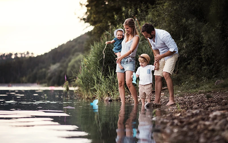 Mother and father with two young children playing at the edge of a river,