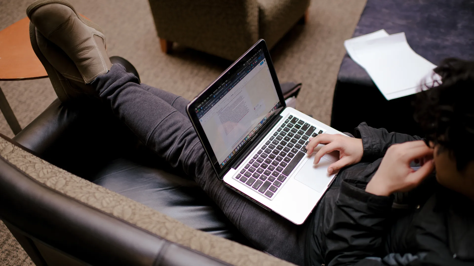 Houghton Universitystudent lounging on couch with laptop.
