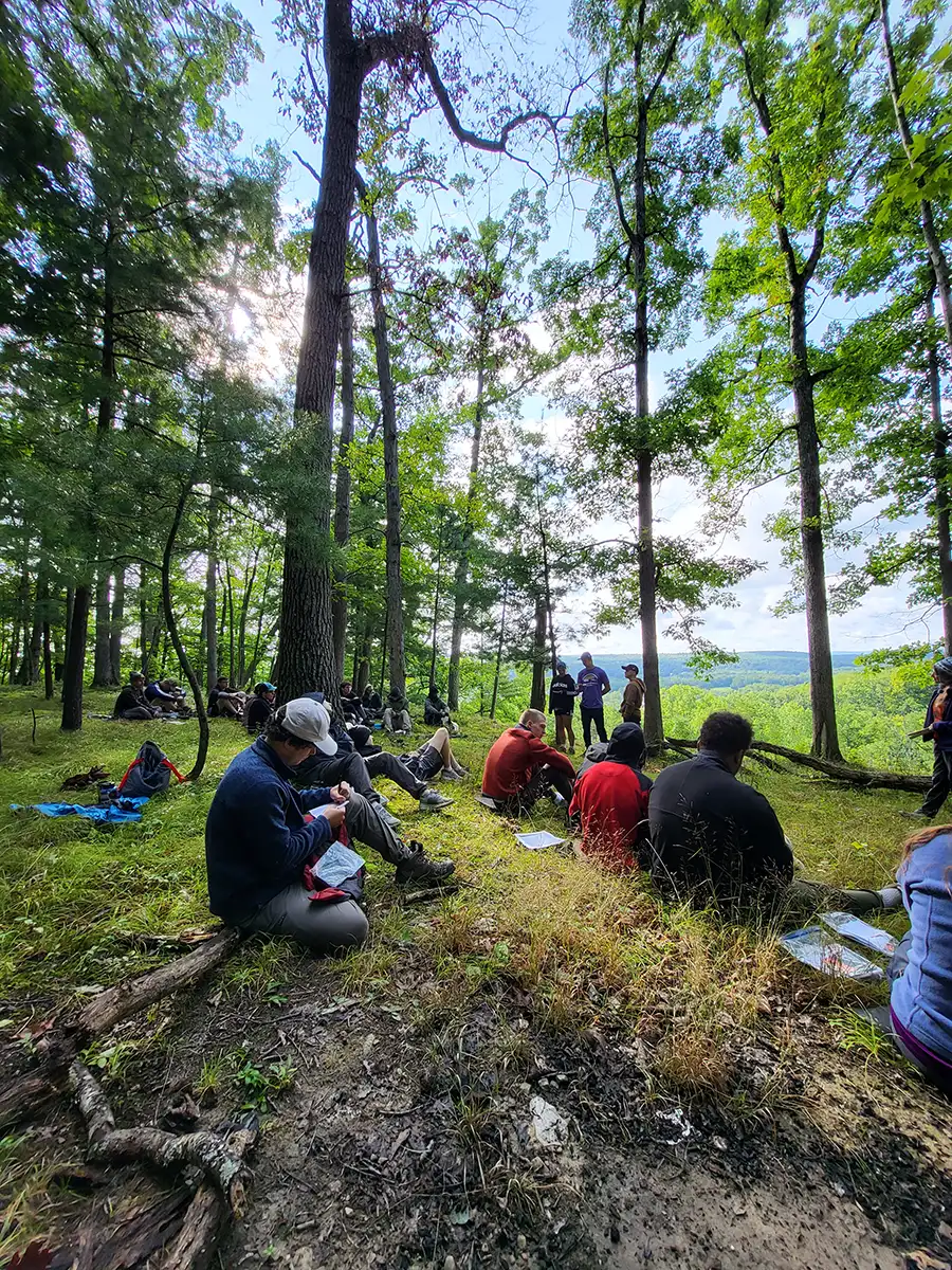 Group of ����ר�� Highlander Adventure students listening to group leaders in forest.