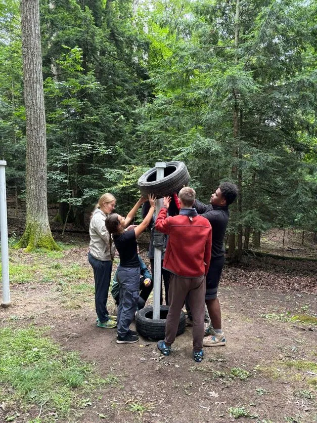 Houghton UniversityHighlander Wilderness Adventure students working on solving tire obstacle.