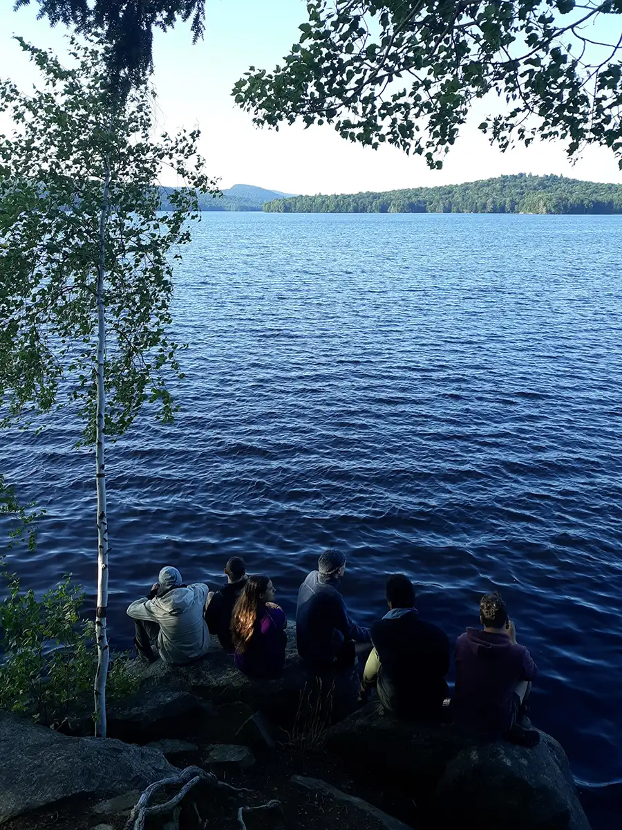Group of ����ר�� Highlander Wilderness Adventure students sitting by shoreline.