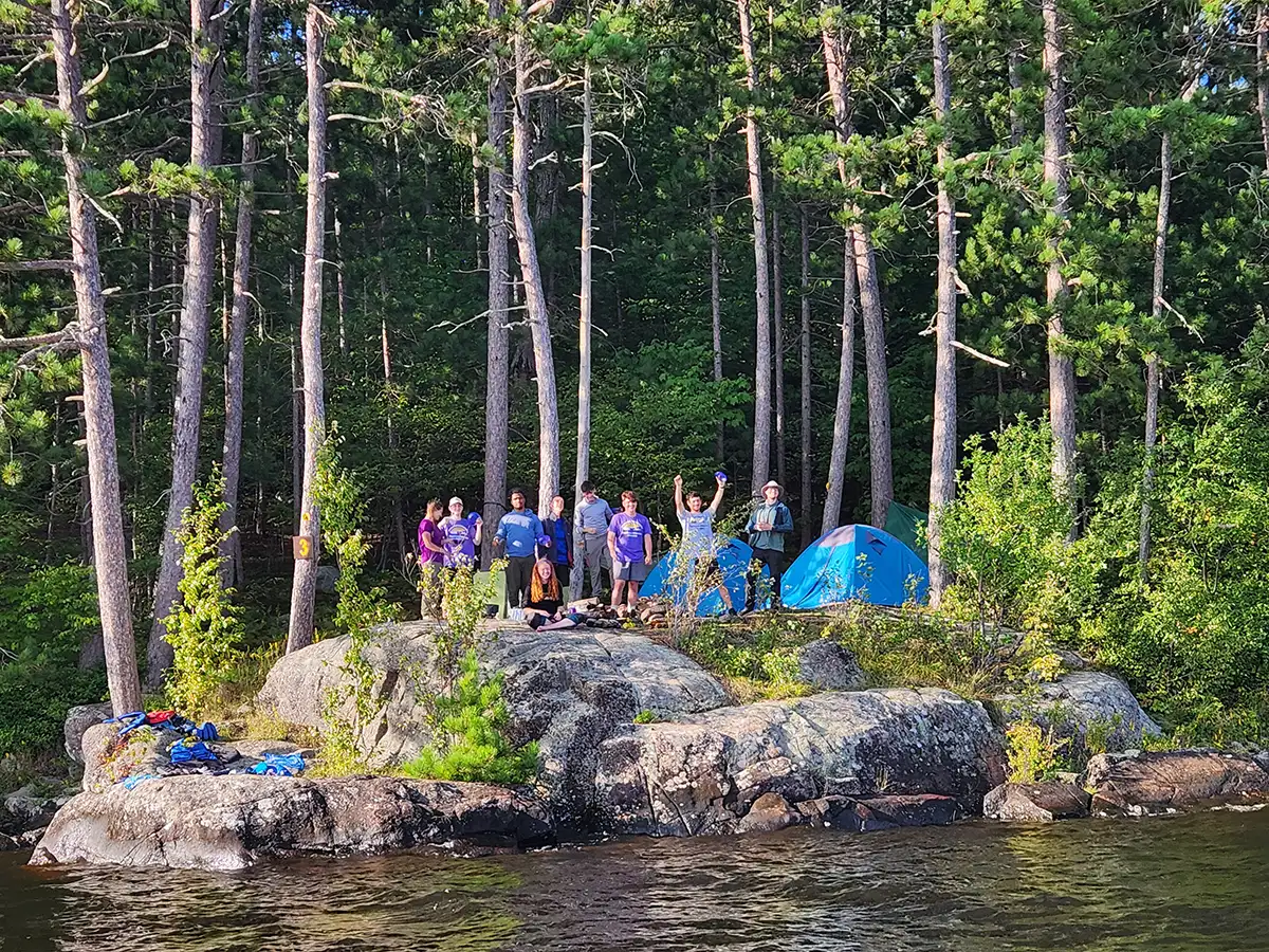 Houghton UniversityHighlander Wilderness Adventure students waving from shoreline.