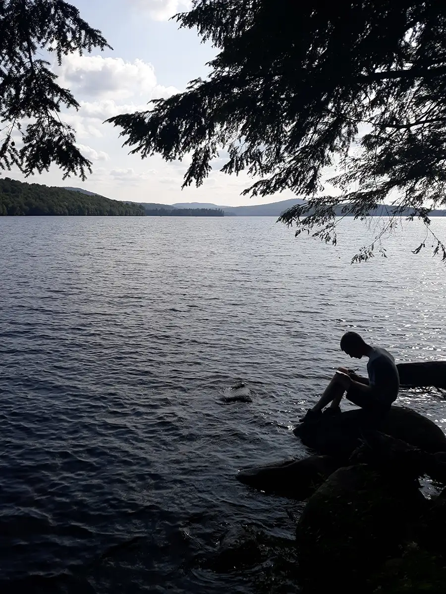 Houghton UniversityHighlander Wilderness Adventure student sitting by lake.