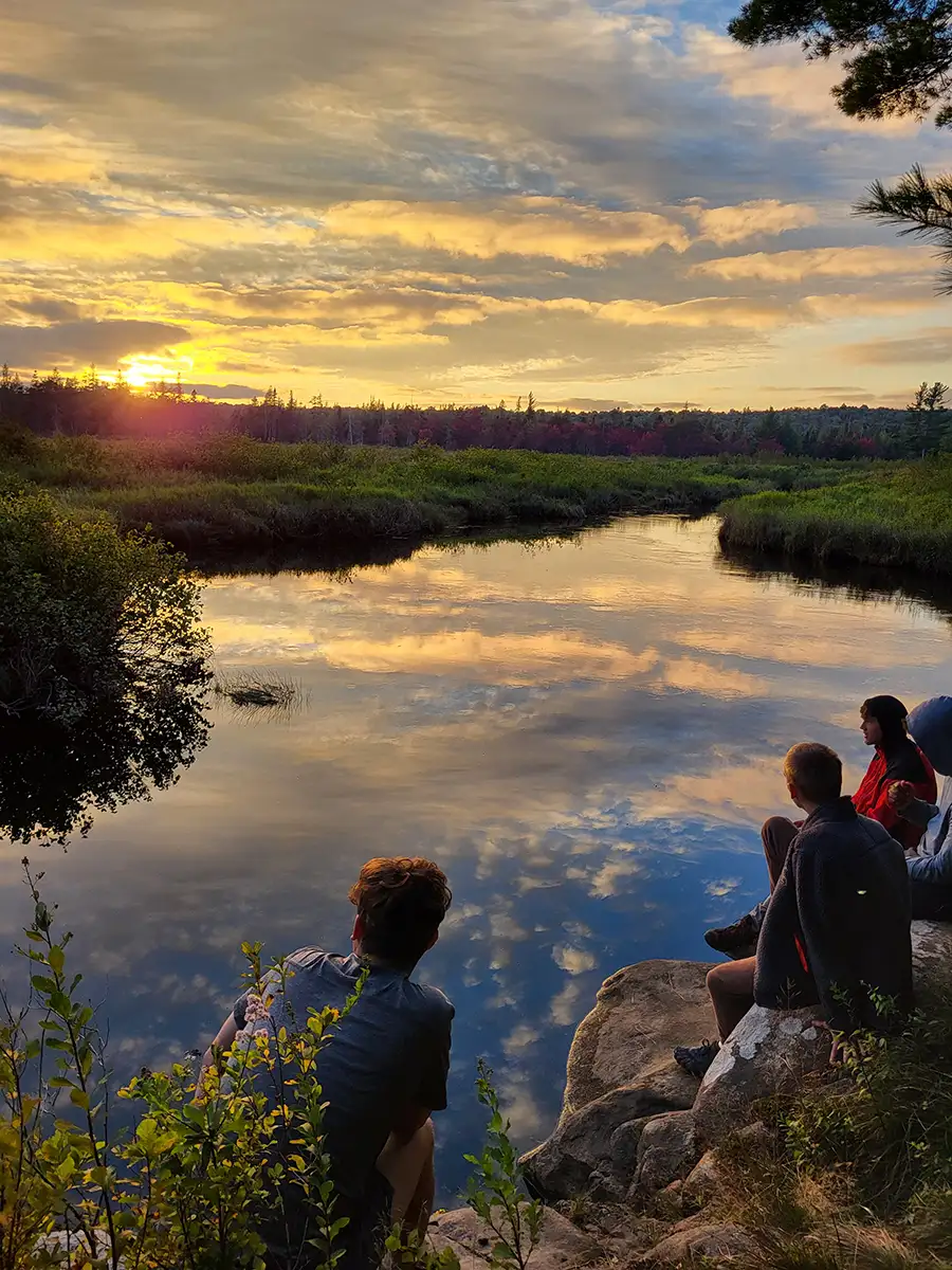 Houghton UniversityHighlander Wilderness Adventure students watching sunset over lake with reflection.