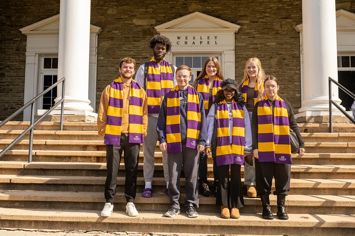 A group of ����ר�� students standing on chapel steps wearing their purple and gold scarves.