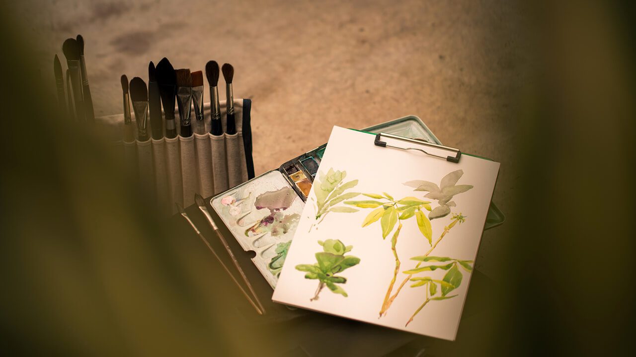 Water color painting with brushes on table.