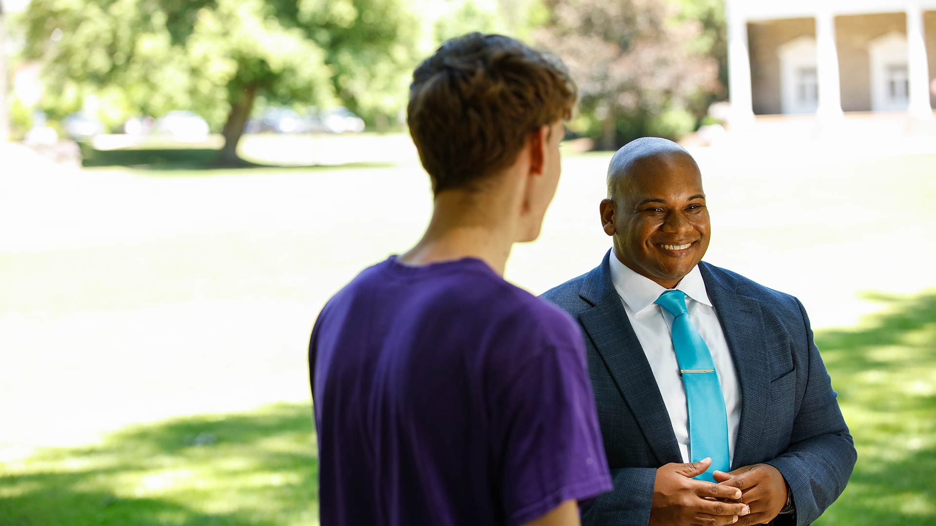 President Lewis speaking with a student in front of the Chapel Quad