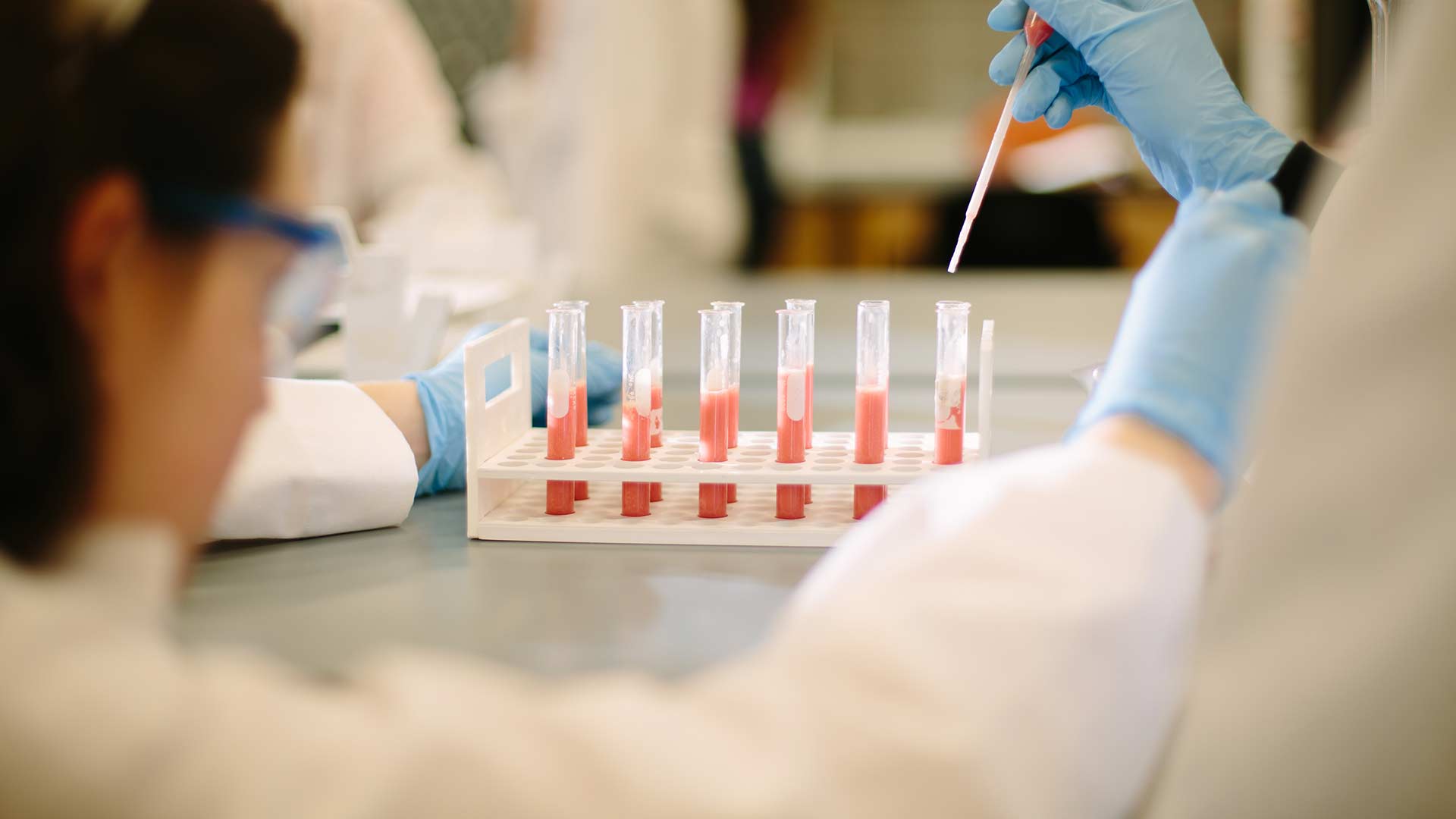 student filling test tubes in science lab