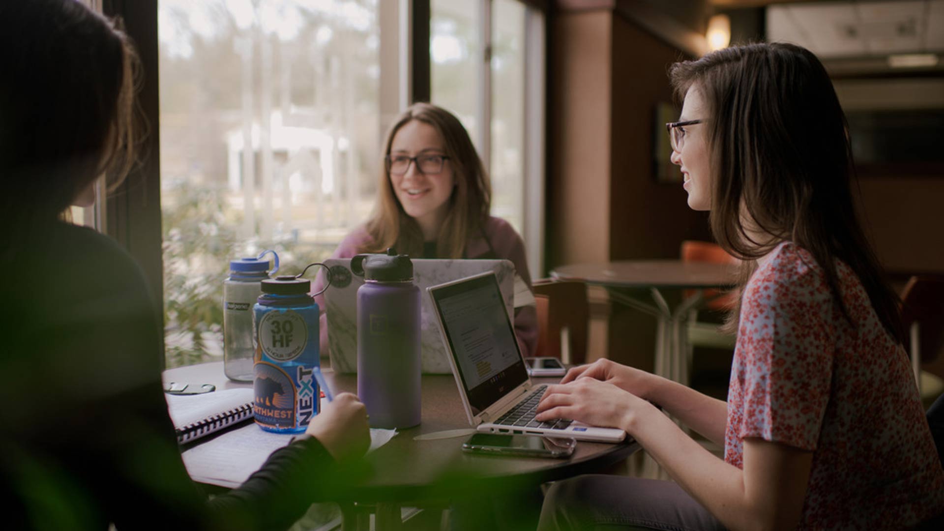 Early college students sitting at table with laptops earning college credit in high school through Houghton University.
