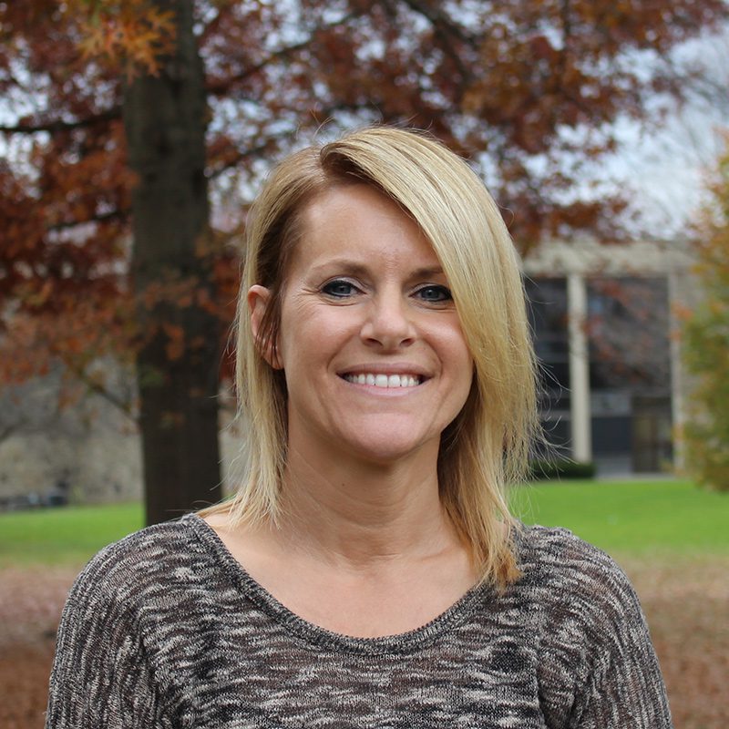 Wendy Fox standing outside on Houghton's campus on fall day.