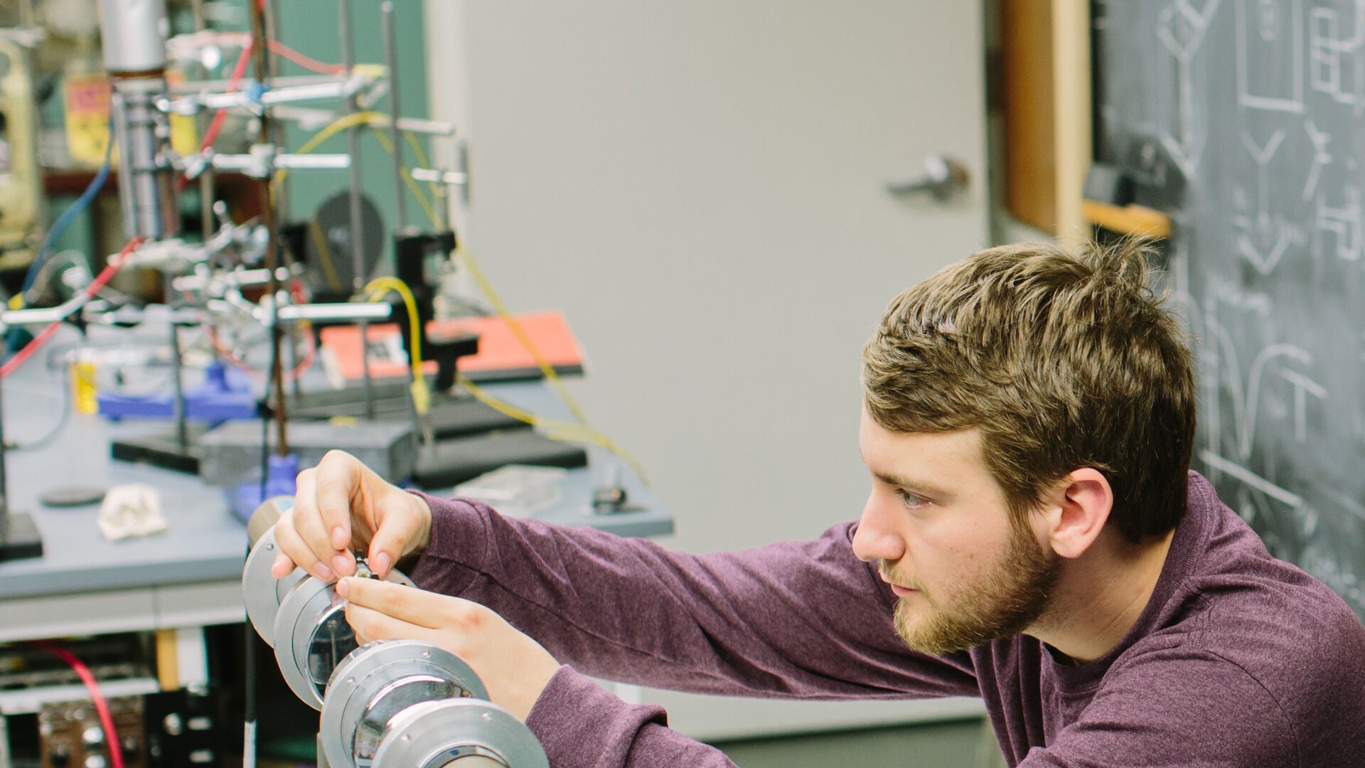 Houghton physics student working with instrument in lab.
