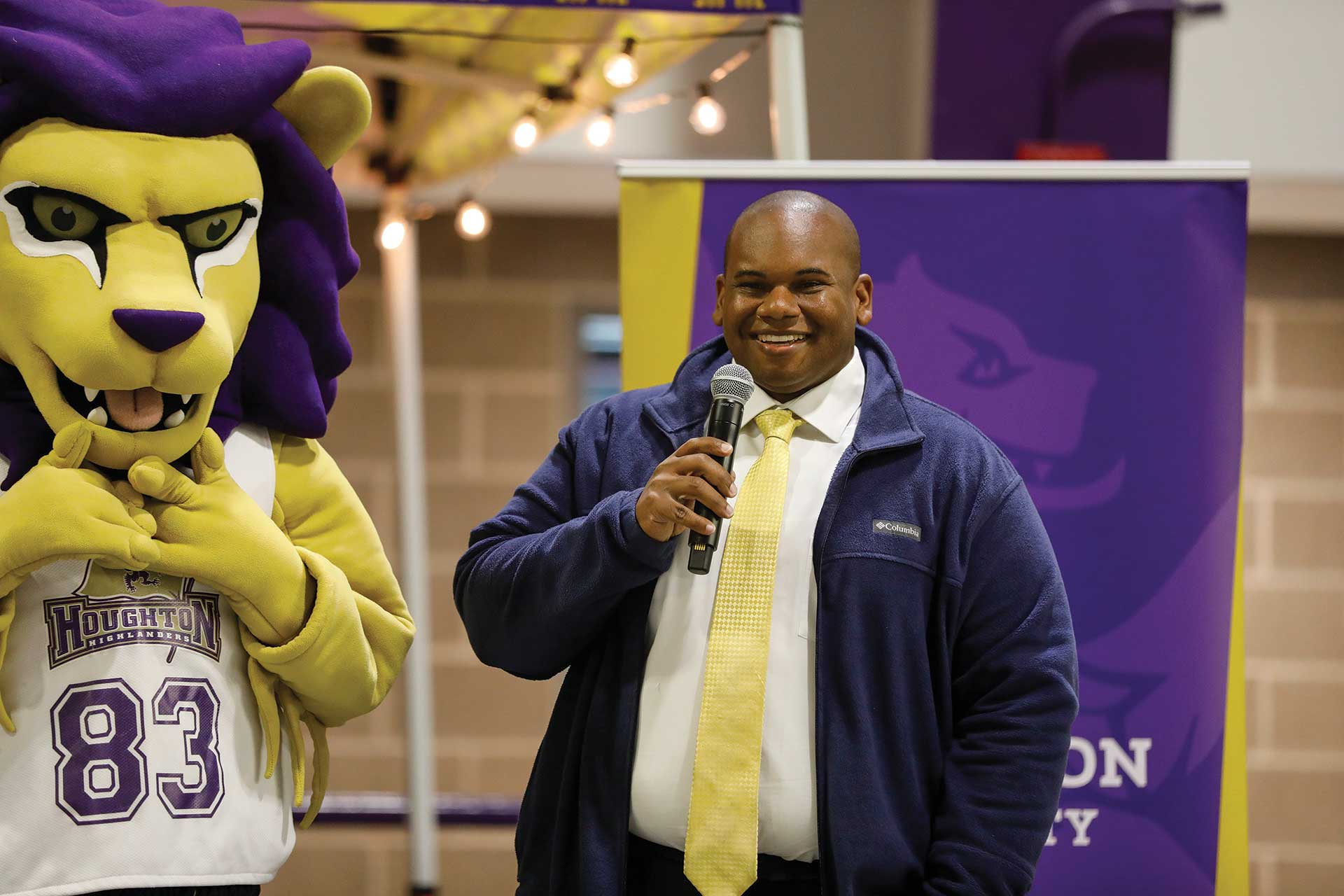 Houghton President, Wayne Lewis standing with microphone next to Luckey at Homecoming.