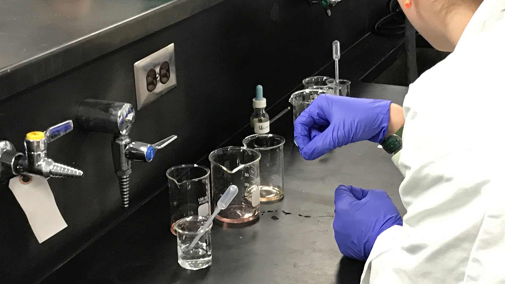 Student using beakers to measure pH in a science lab