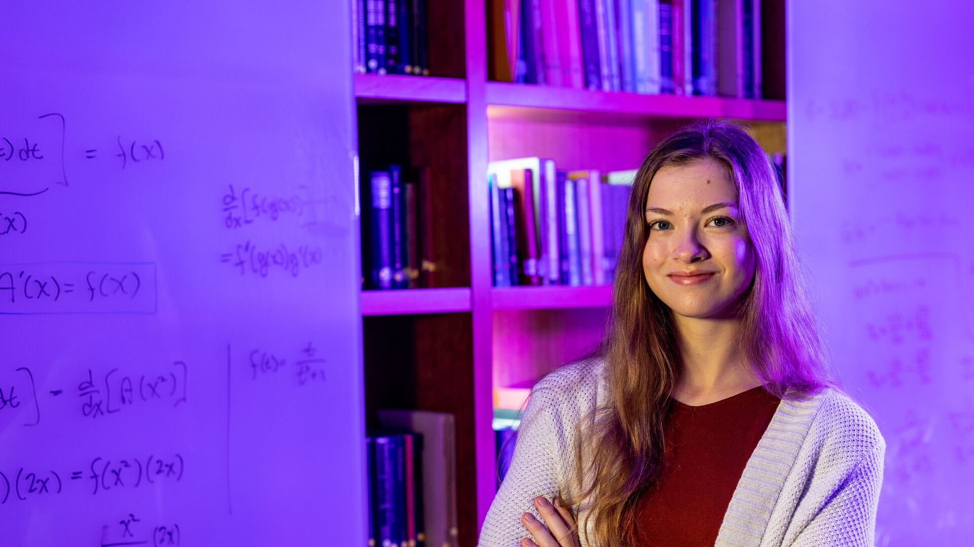 Houghton alumna Haley DeJager standing by whiteboards with math equations.