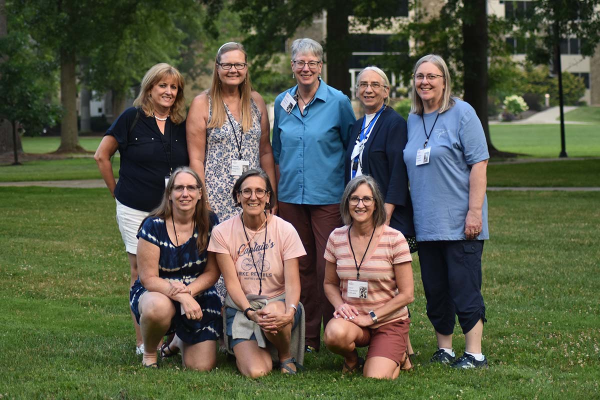 Group of alumni standing on campus lawn during their class reunion.