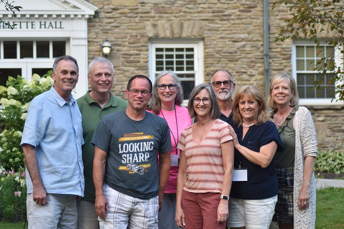 A group of Houghton alumni standing for photo on campus lawn.