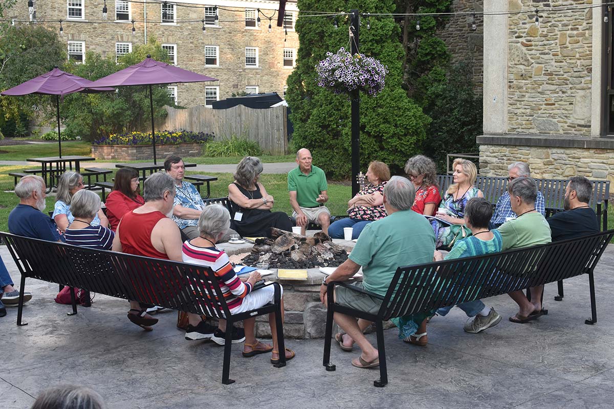 A group of Houghton alumni sitting on outdoor chairs outside the campus center.