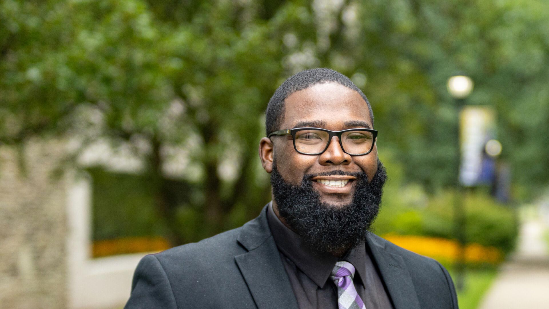 Houghton professor Torrance Jones standing on campus in suitcoat and tie.