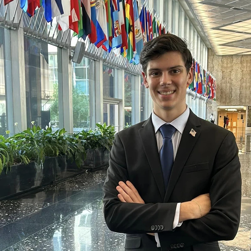 Houghton student Cody Johnson standing in hallway with international flags.
