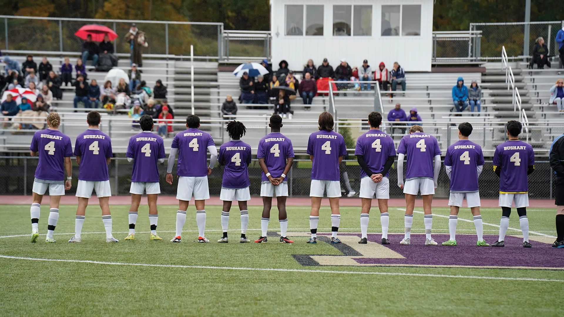 Houghton men's soccer team standing on field in line.